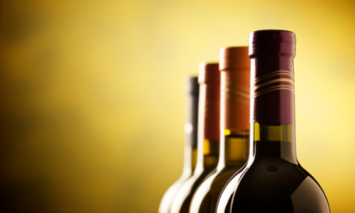 foto ilustrativa: garrafas de vinho com fundo amarelo